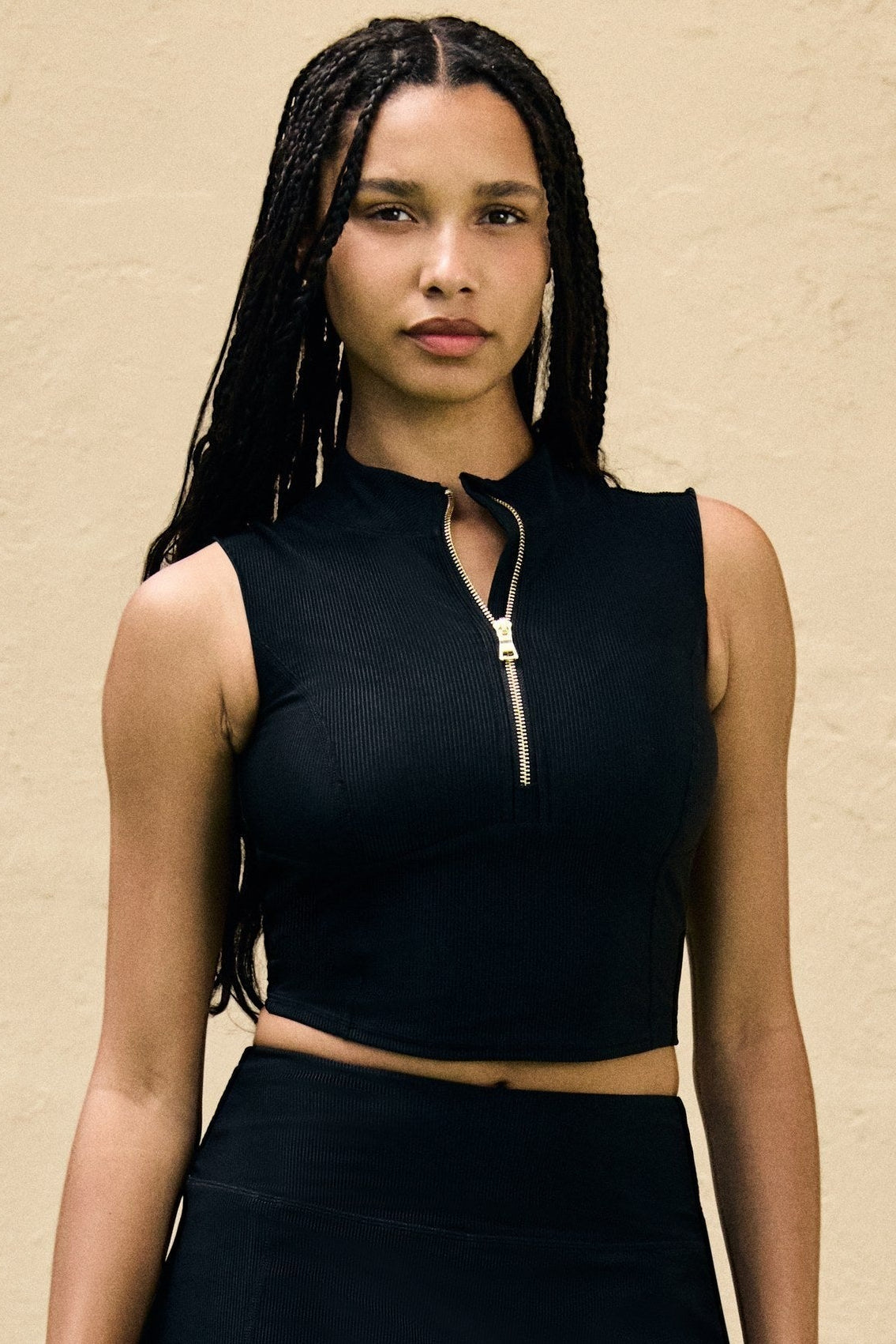 Tennis Club black ribbed knit skirt with built-in shorts worn by a model with a matching zip-up top on a tennis court